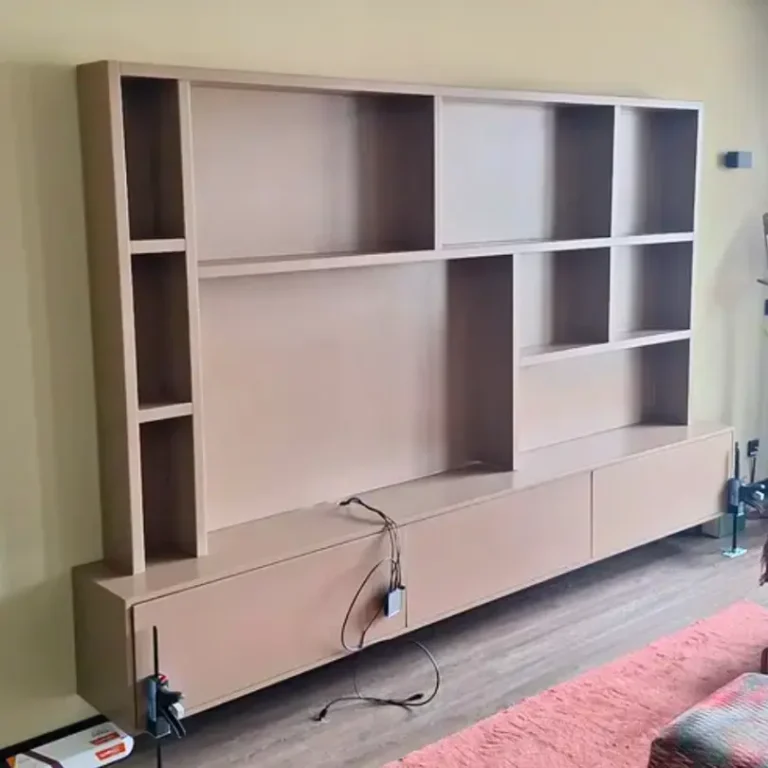 Een zwevend, lichtbruin TV-meubel aan een geelgroene muur, met een ladekast en open vakken.